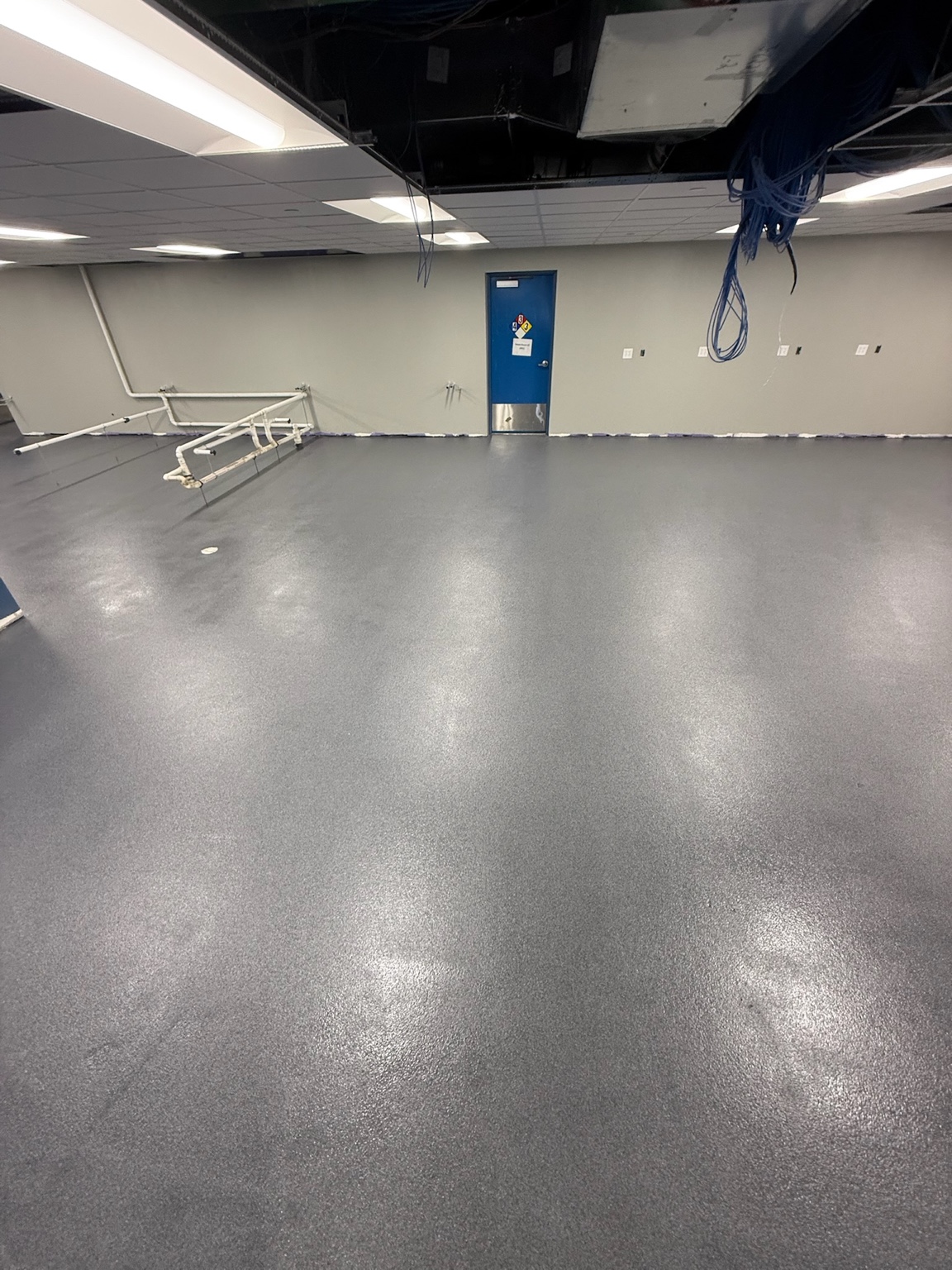 New gray epoxy flooring across a large Iowa commercial room during installation