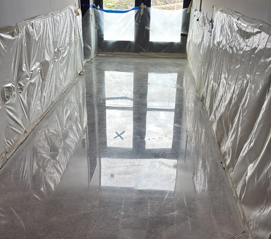 Mirror-polished concrete hallway floor reflecting the windows in a masked-off Des Moines work area