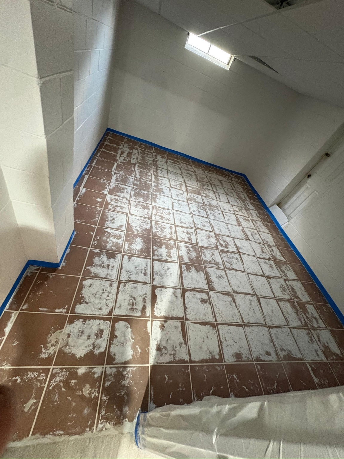 Commercial tile floor masked with blue tape during surface preparation in Des Moines