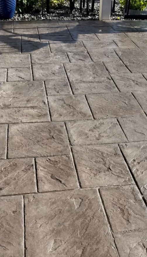 Resealed stamped concrete patio with fresh, even sealer and rich color in Des Moines