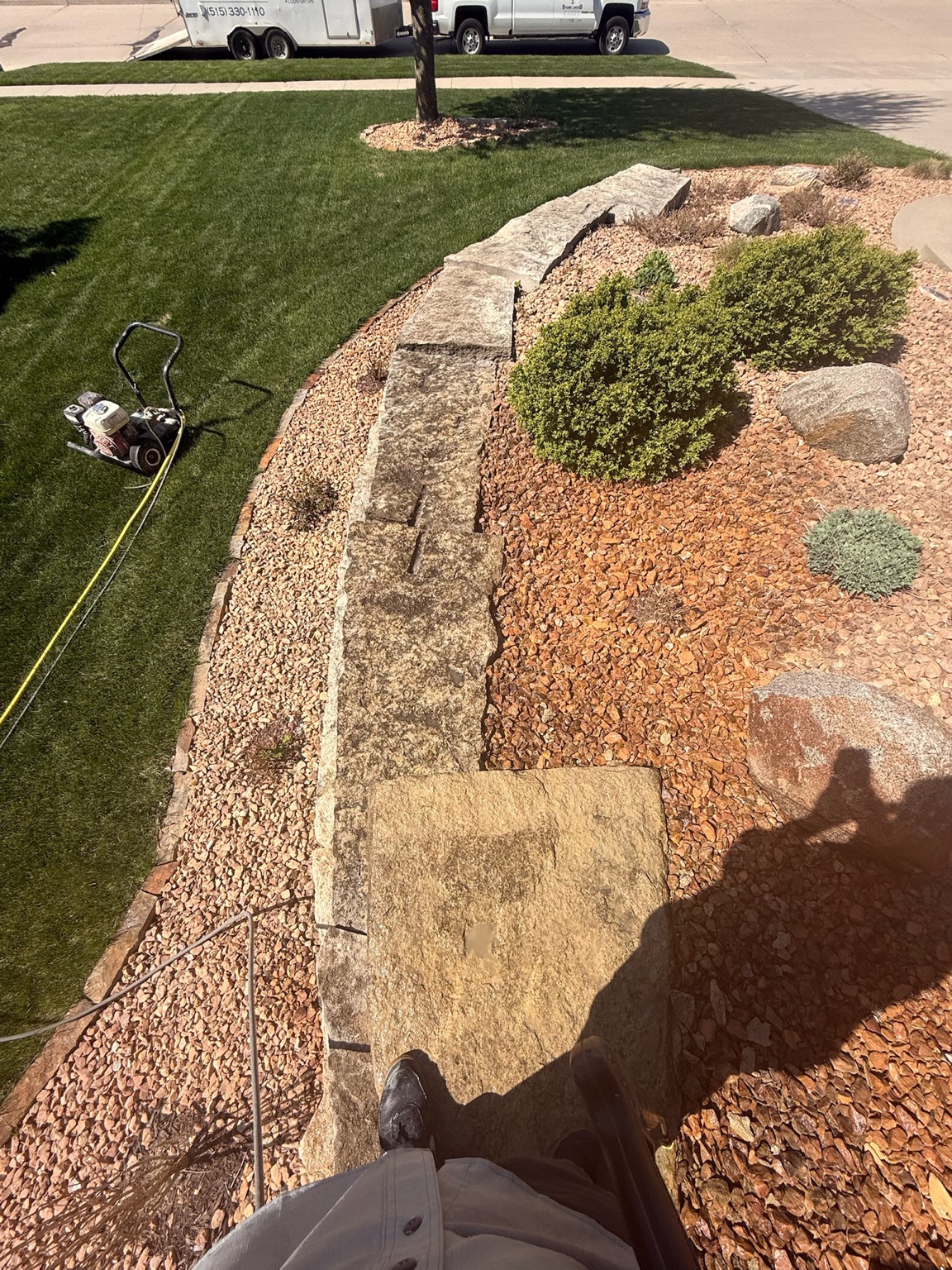 Stone retaining wall during restoration beside a Des Moines lawn