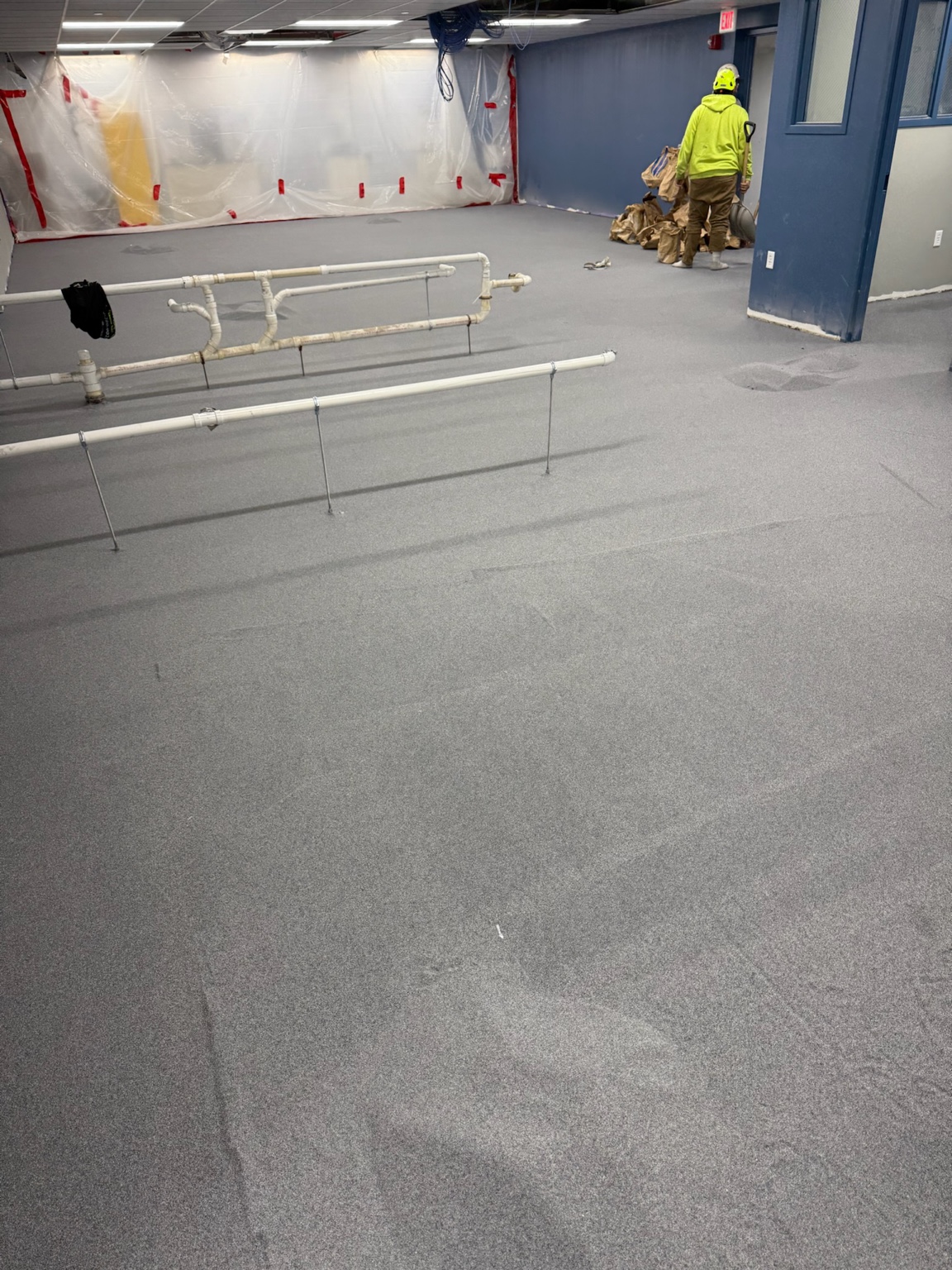 Worker installing a gray epoxy floor in a large Iowa commercial facility